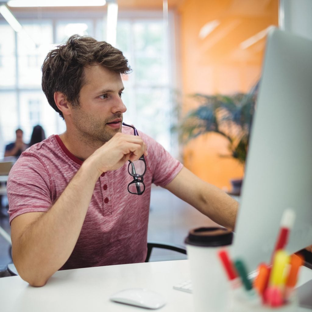 Business owner reviewing his website on a desktop monitor in a bright modern office