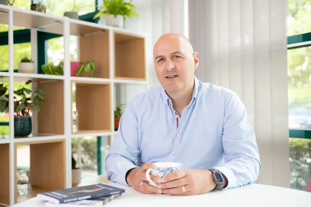 Colin Tapscott, Everyday Leader coach, seated at a table with a coffee in a relaxed portrait