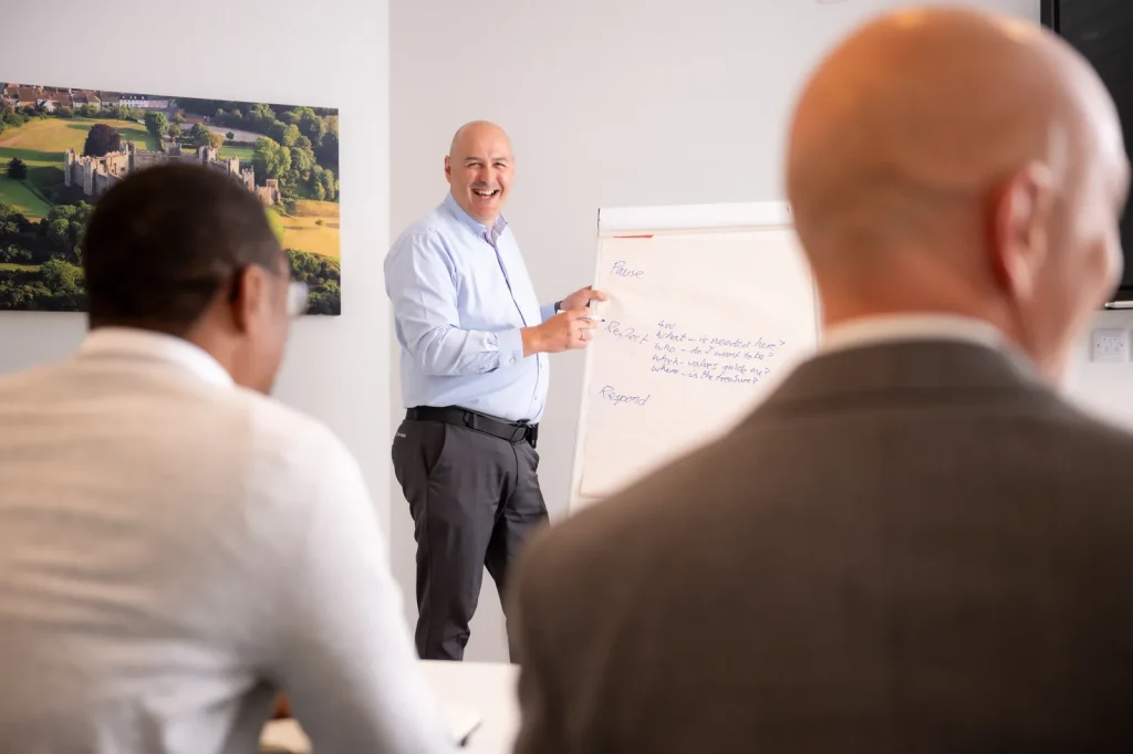 Colin Tapscott facilitating a leadership workshop at a flip chart with two participants