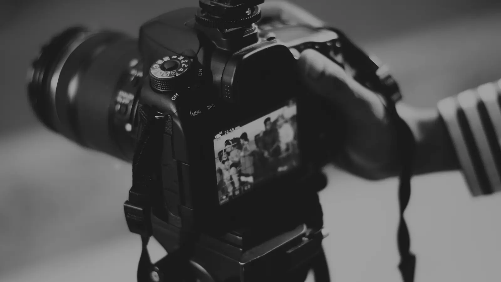 Rear view of a camera on a tripod filming a group of people shown on the camera screen during a video content shoot in Bury St Edmunds